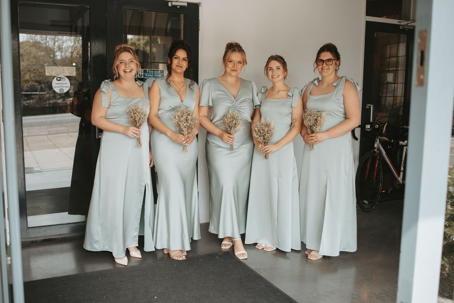 Bridesmaids in pale blue dresses pose together in a casual group photo.