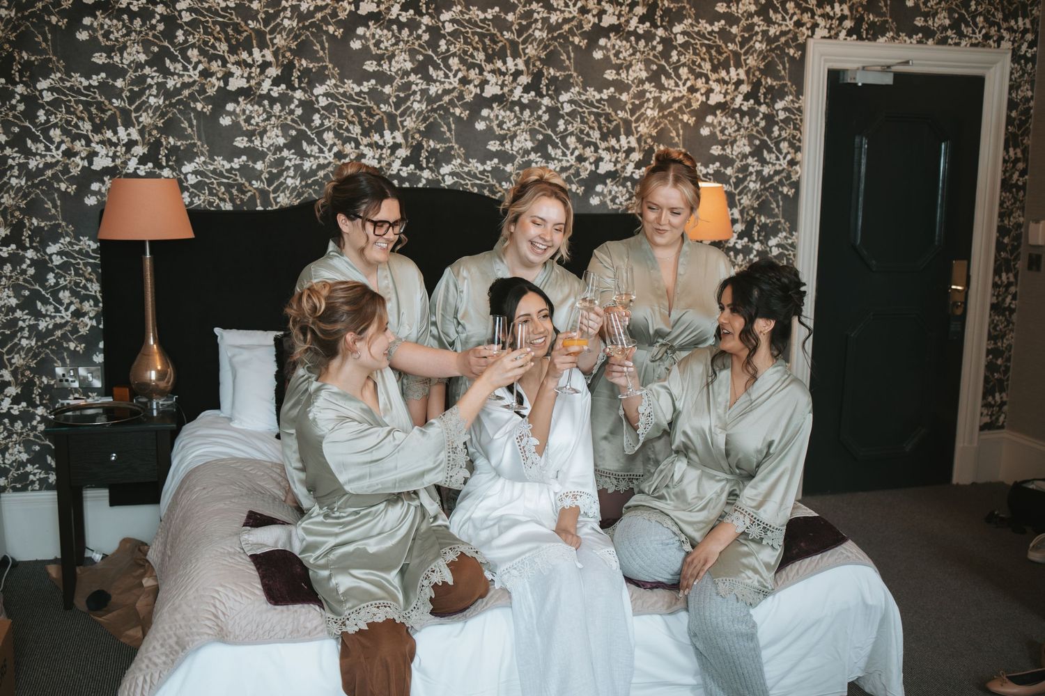 A group in matching silver robes laughs together during a wedding celebration.