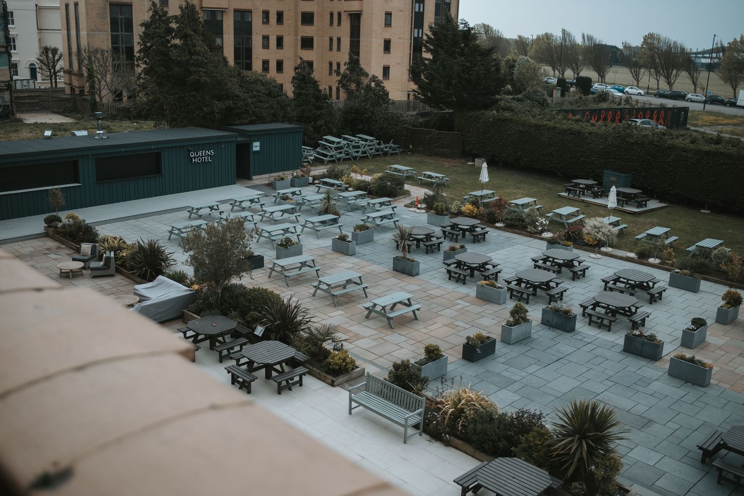 Aerial view of a parking lot with scattered cars and buildings in the background.