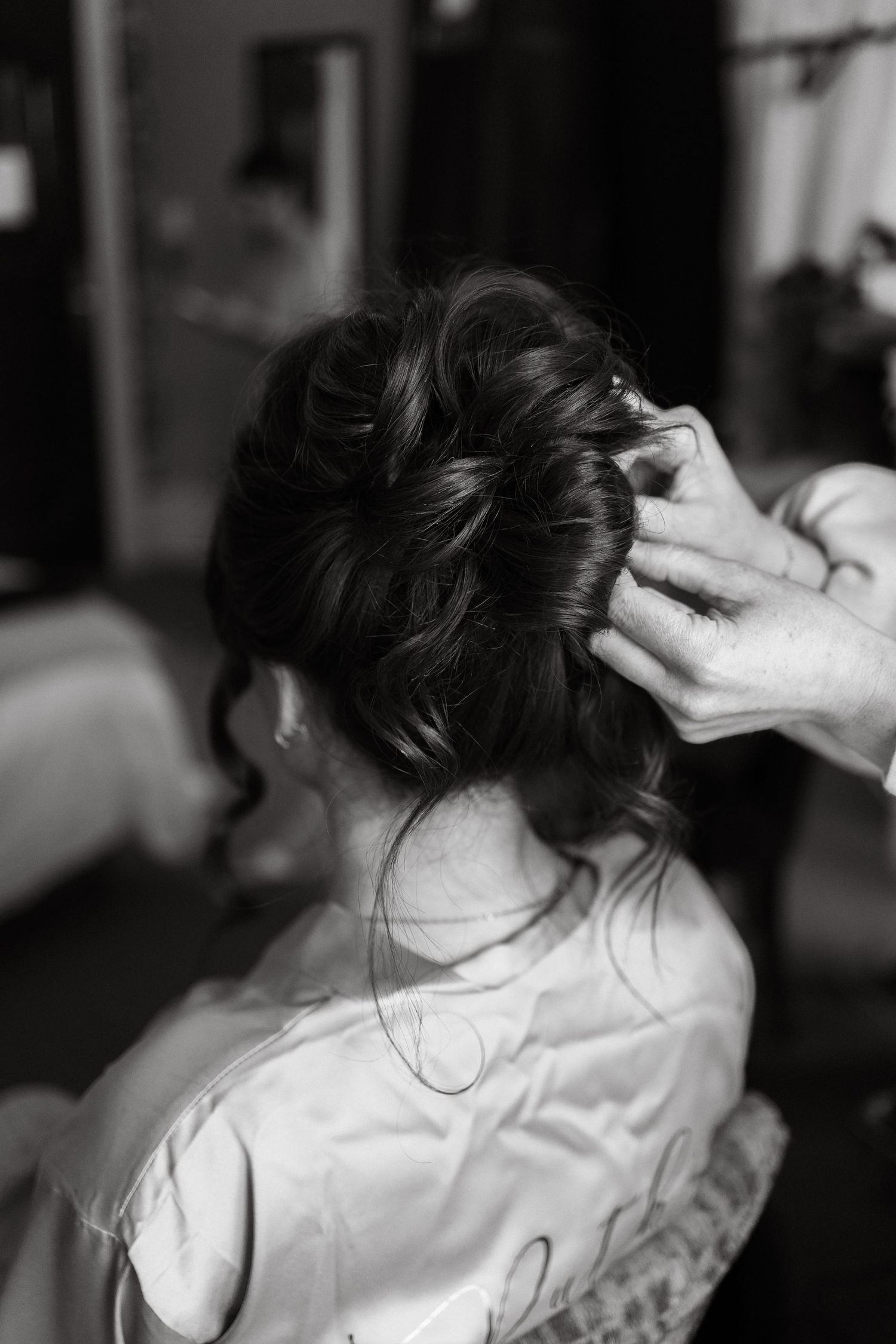 Black and white photo of bridal hair being styled before the wedding ceremony.