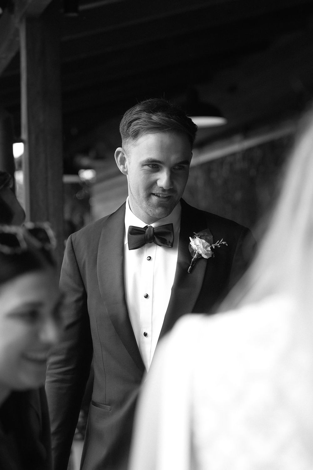 Black and white close-up photo of someone in a tuxedo with bow tie at formal event.