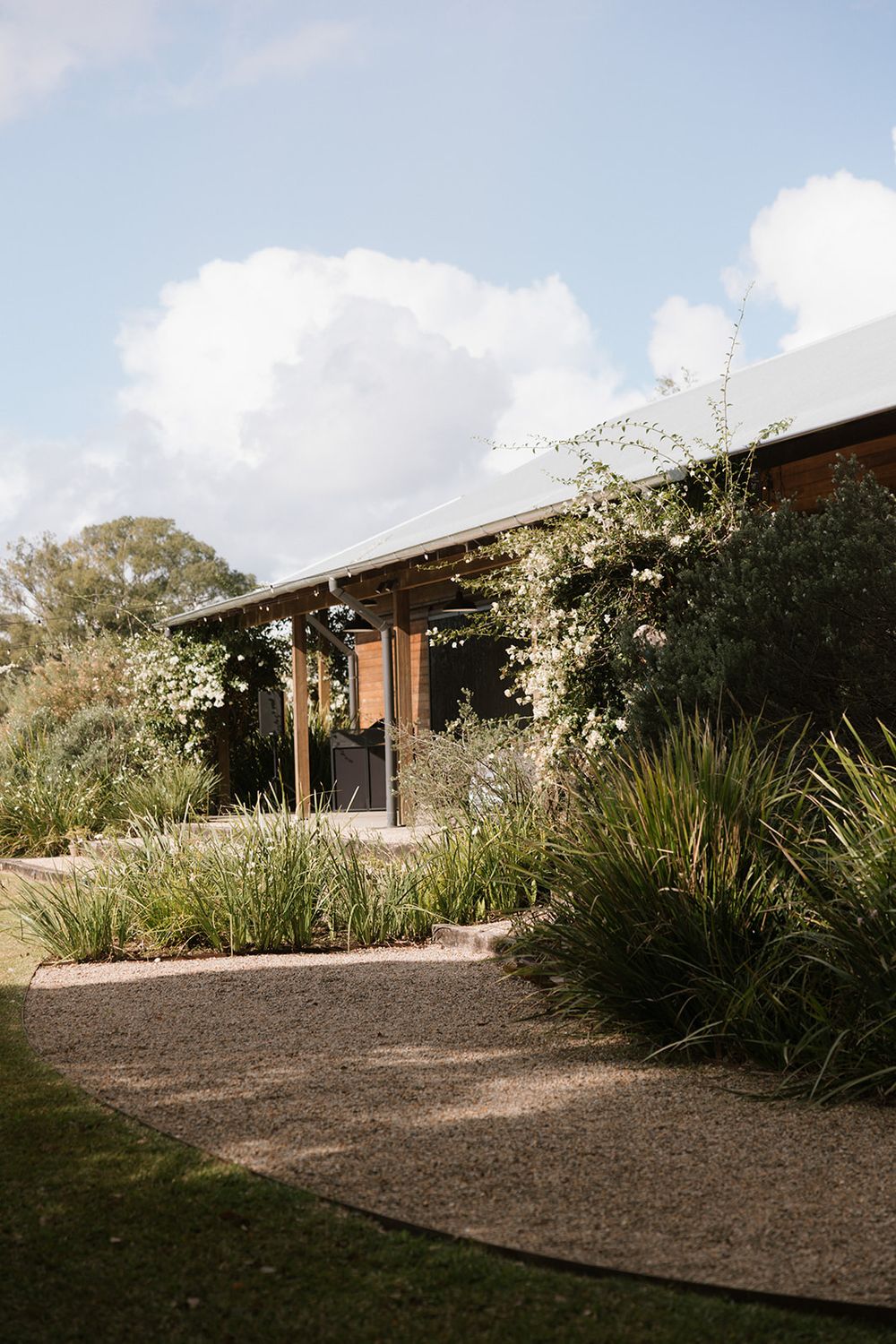 Modern brick house with drought-resistant landscaping and native plants under a cloudy sky.
