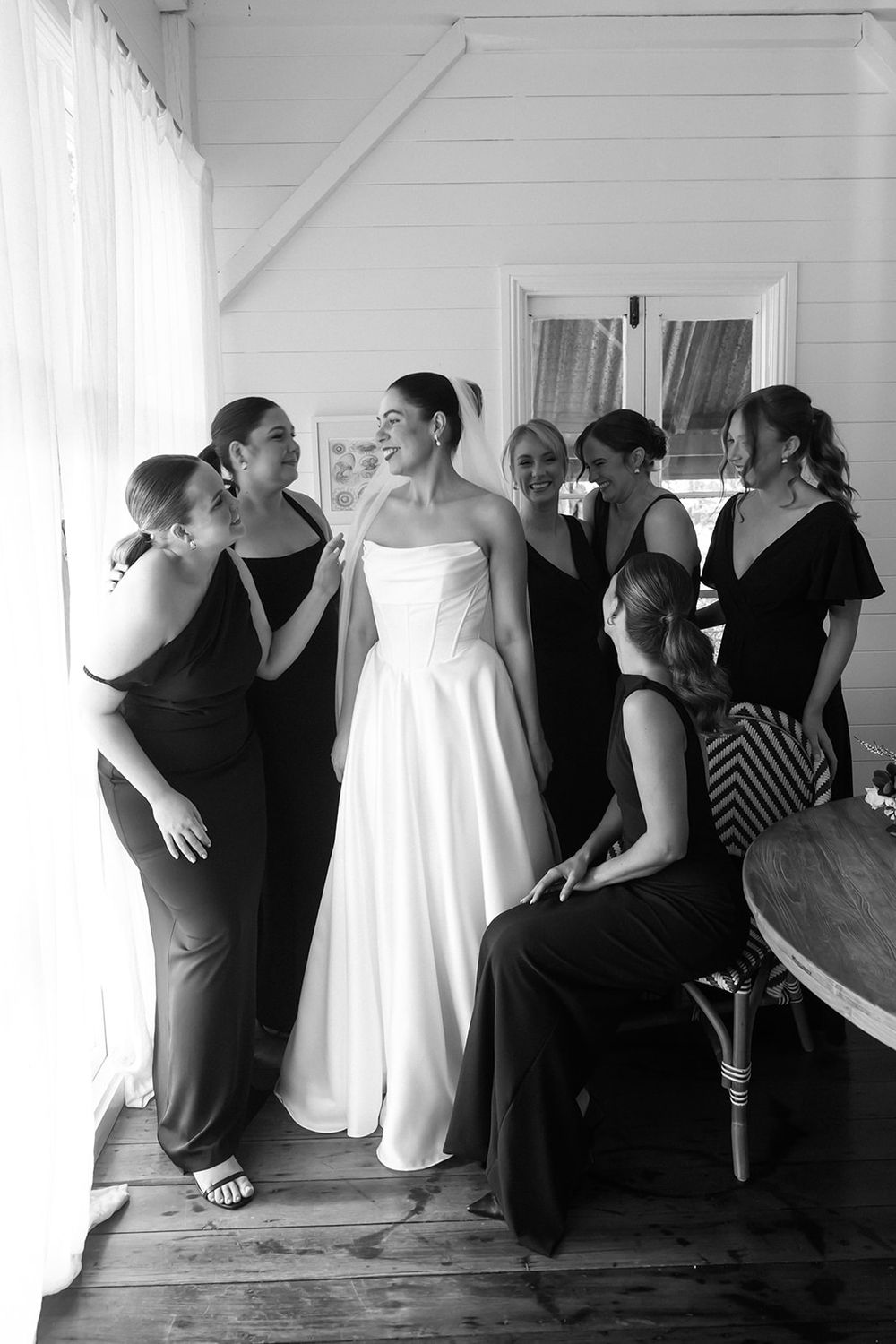 A series of black and white photos showing a bride in a white dress getting ready with her bridal party.