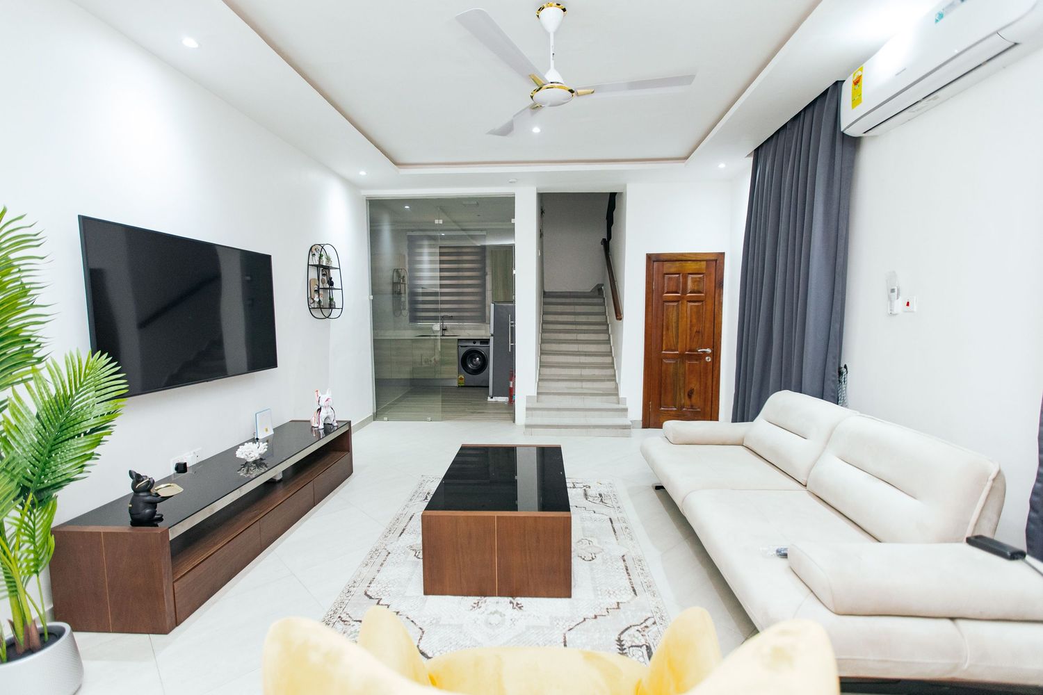 Sleek white interior showcasing a wall-mounted TV unit and comfortable seating arrangement.