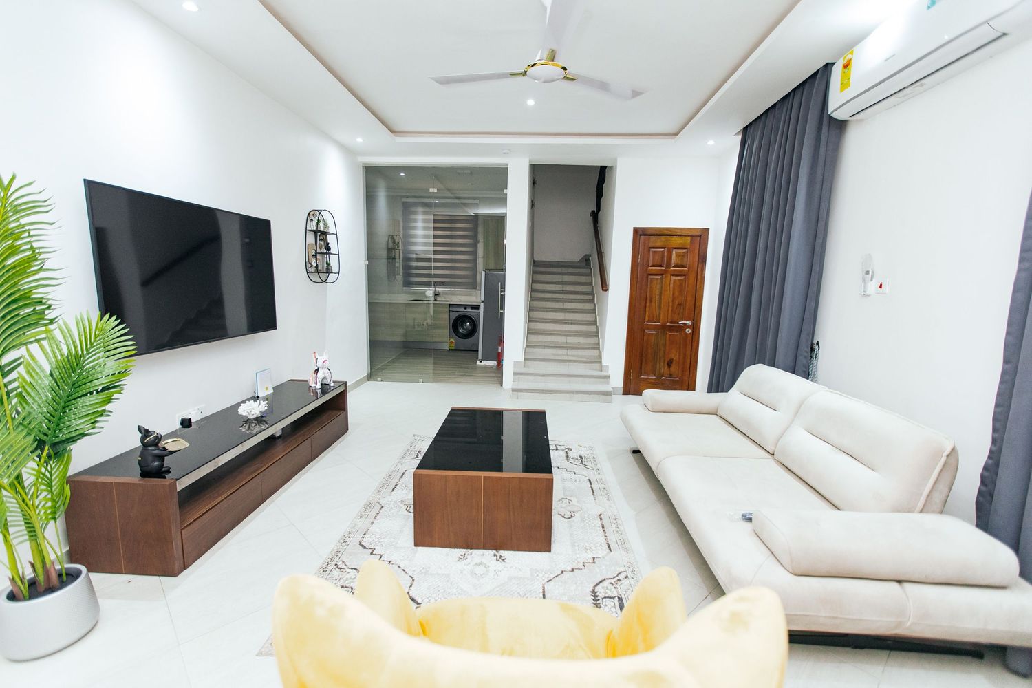 Minimalist living space featuring grey curtains, wooden storage unit, and white walls.