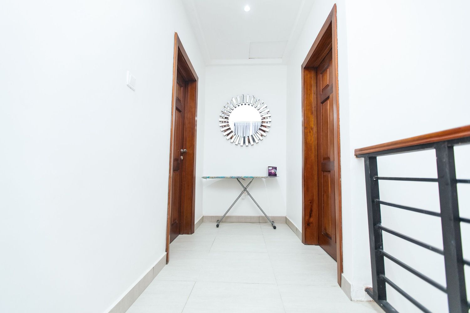 Minimalist interior hallway with white walls, wooden trim, and modern ceiling fixtures.