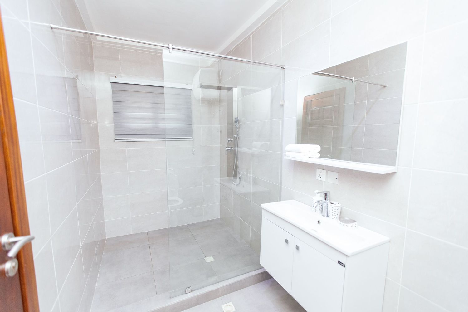 Modern white bathroom with glass shower enclosure and floating vanity.
