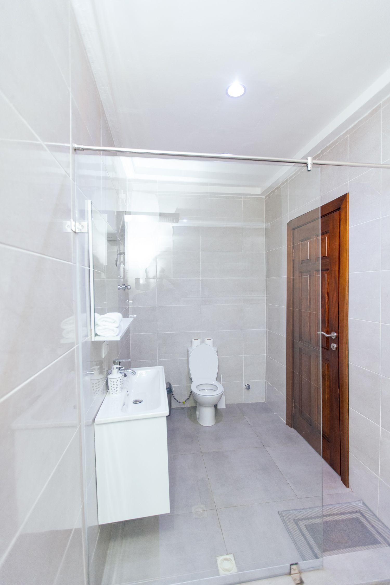 Contemporary bathroom with wooden door, white tiled walls, and modern fixtures.
