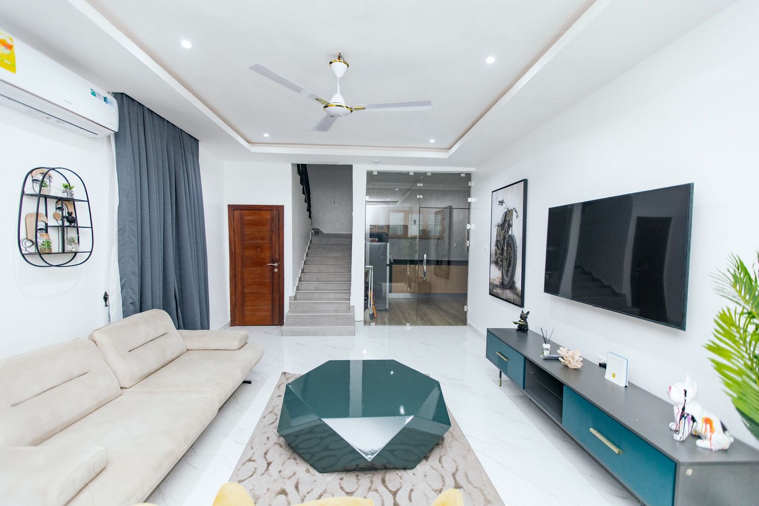 Spacious living room with mounted TV, teal accent wall, and modern decor elements creating a stylish ambiance.