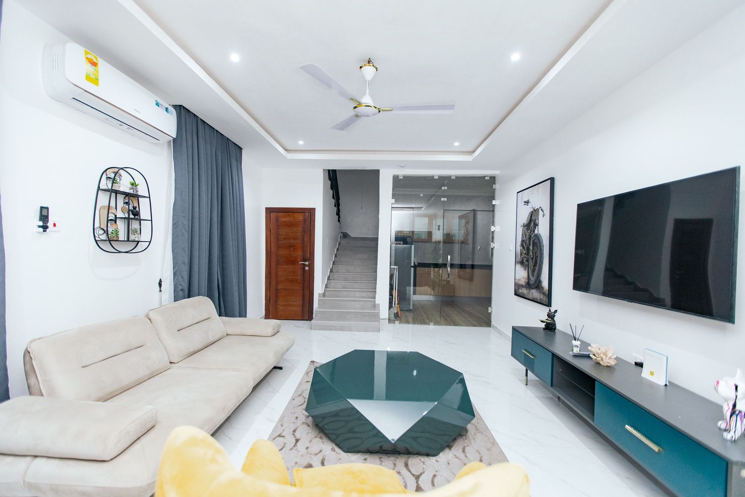 Contemporary living space featuring wall-mounted TV, teal accent wall, and comfortable seating arrangements.