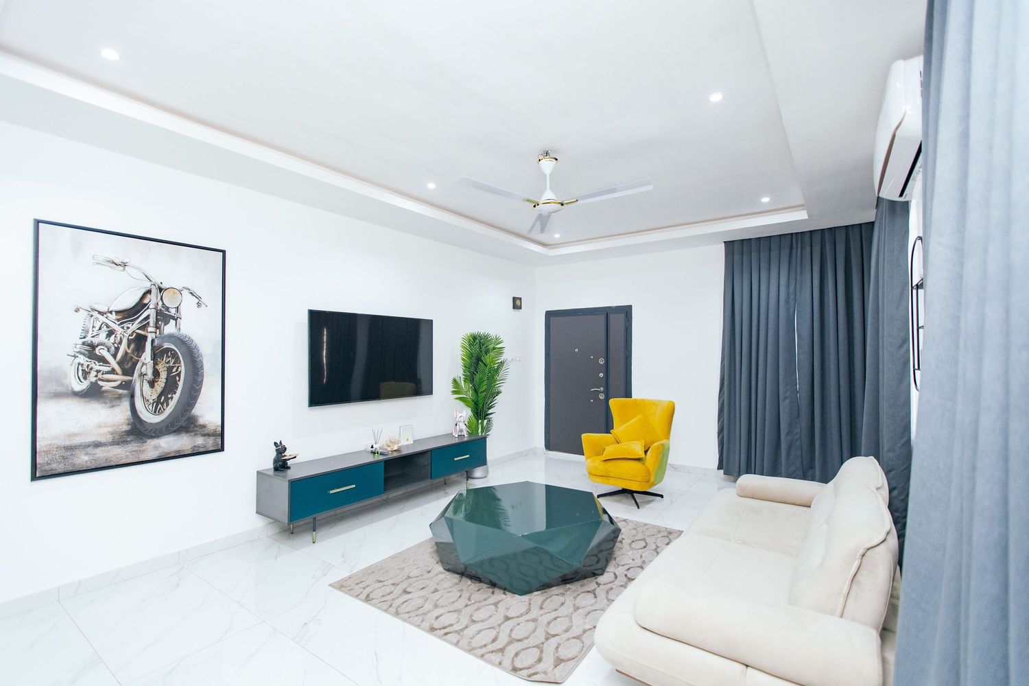 Sleek modern interior featuring white walls, grey drapes, and strategically placed accent furniture.