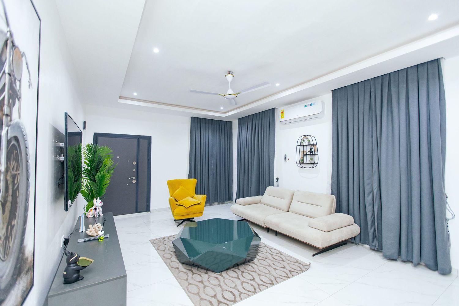 Bright living space with yellow accent chair, teal furniture, and modern wall art in white interior.