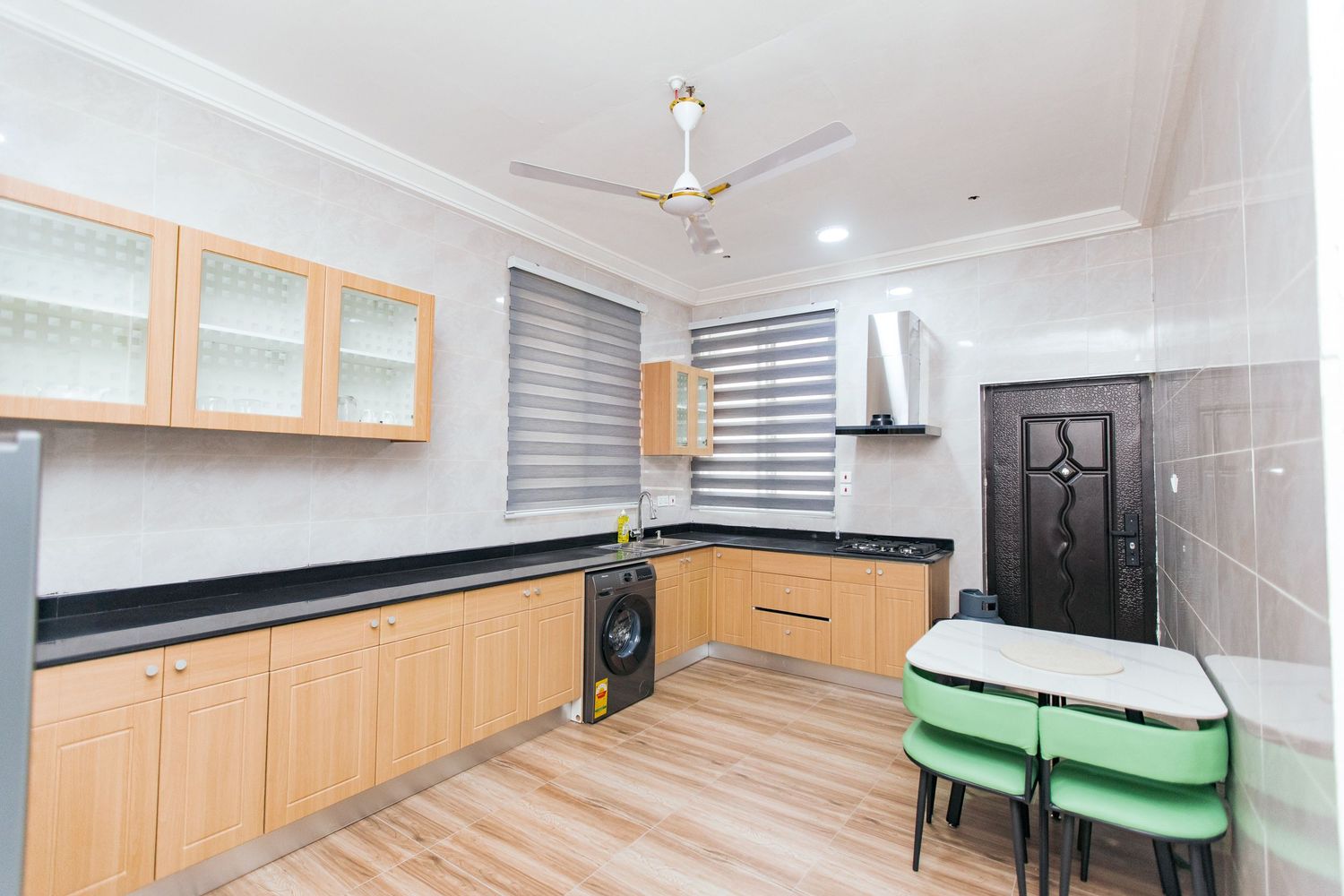 Modern kitchen with wooden cabinets, black countertops, and stainless steel appliances in bright setting.