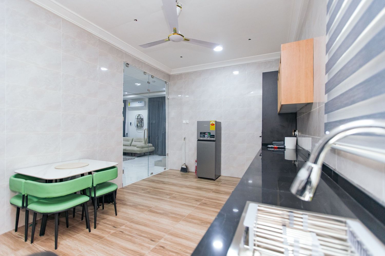 Open concept kitchen and dining area with wooden flooring and green accent seating.