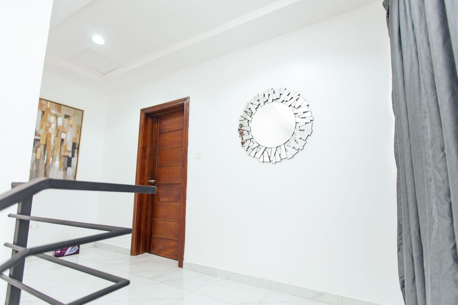 White hallway interior with wooden doors, modern lighting fixtures, and circular wall decor.