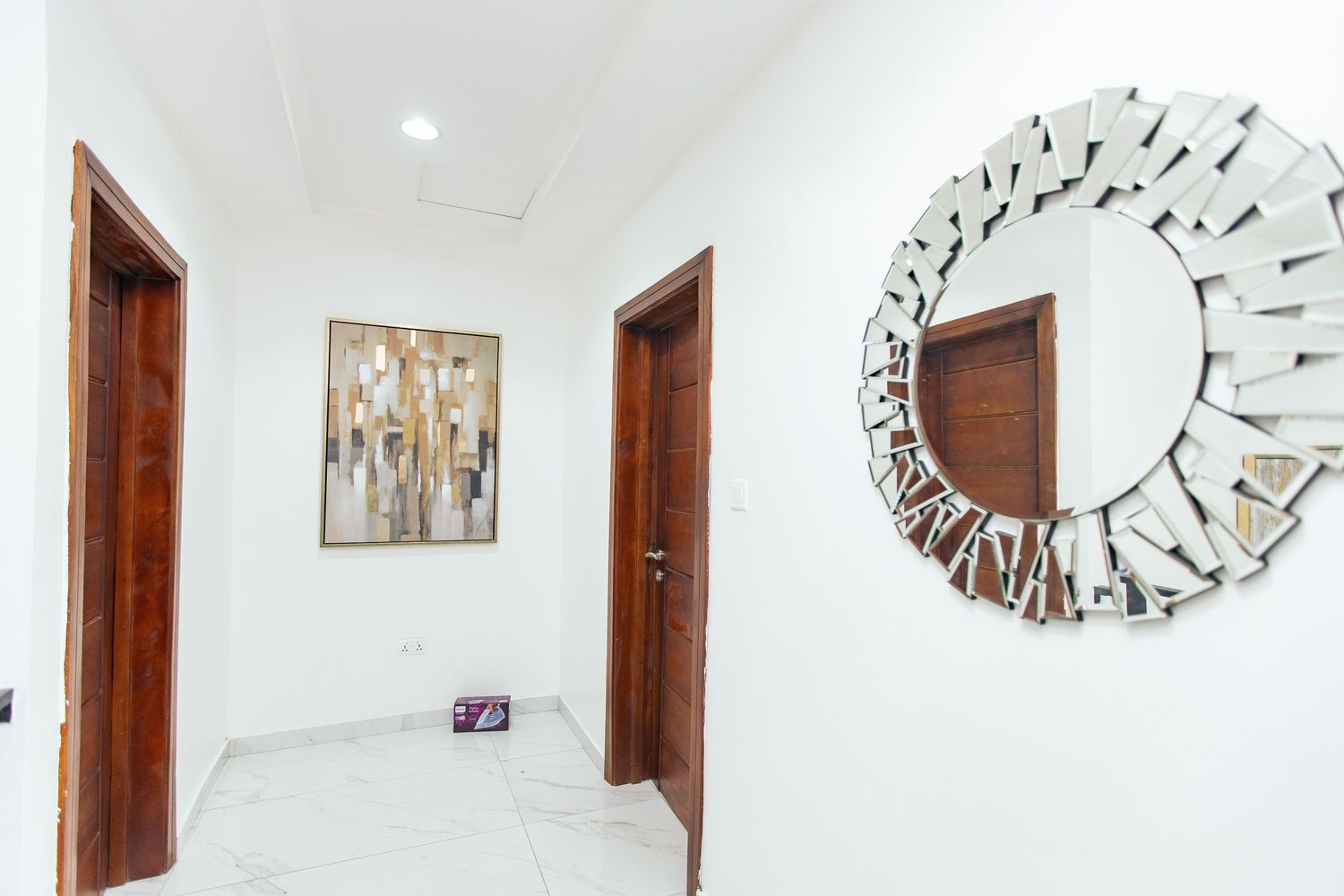 White corridor with decorative circular mirror art pieces and wooden doors.