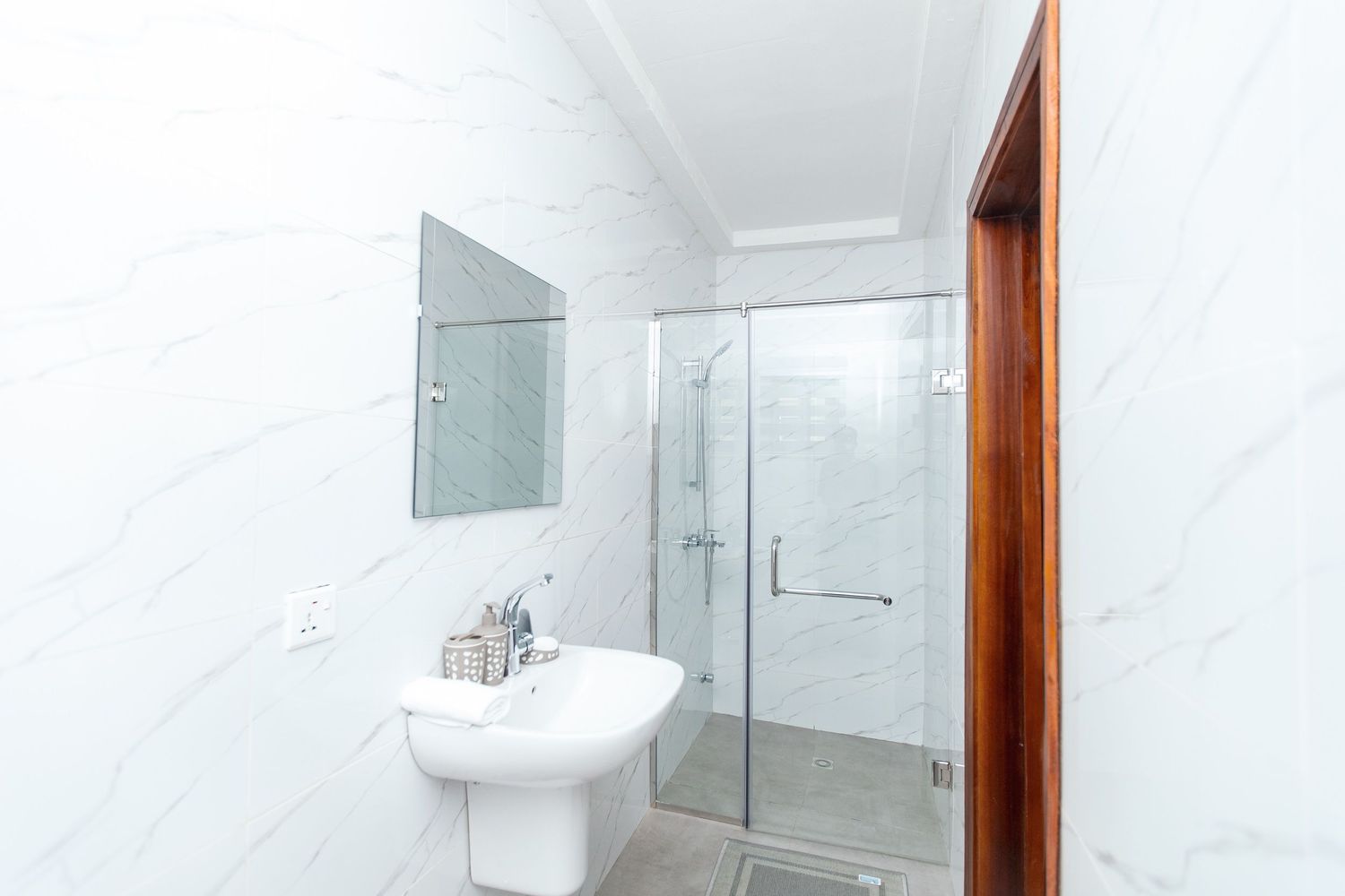 Clean white bathroom with glass shower enclosure and modern fixtures.