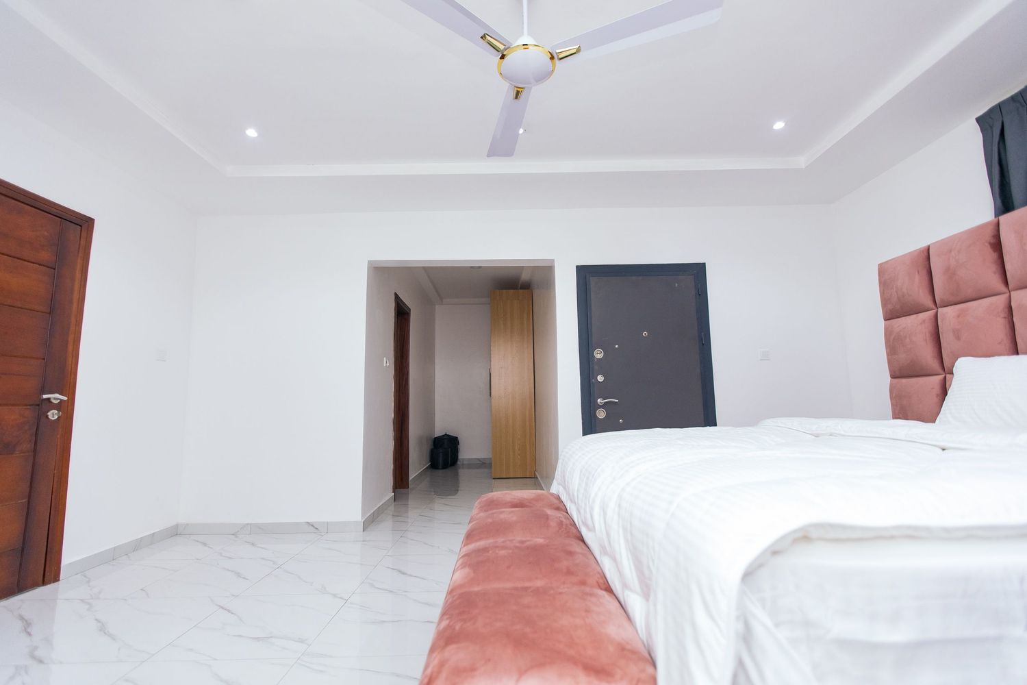 Large empty room with white walls, recessed lighting and pink accent furniture.