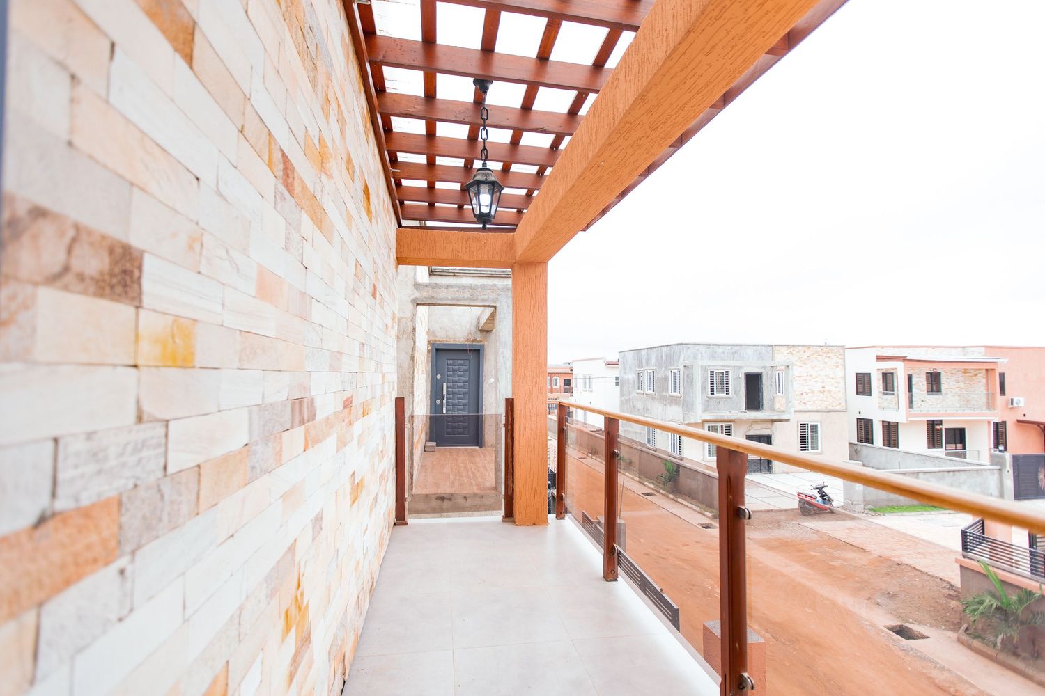 Covered balcony with wooden beams and stone walls offering city views.