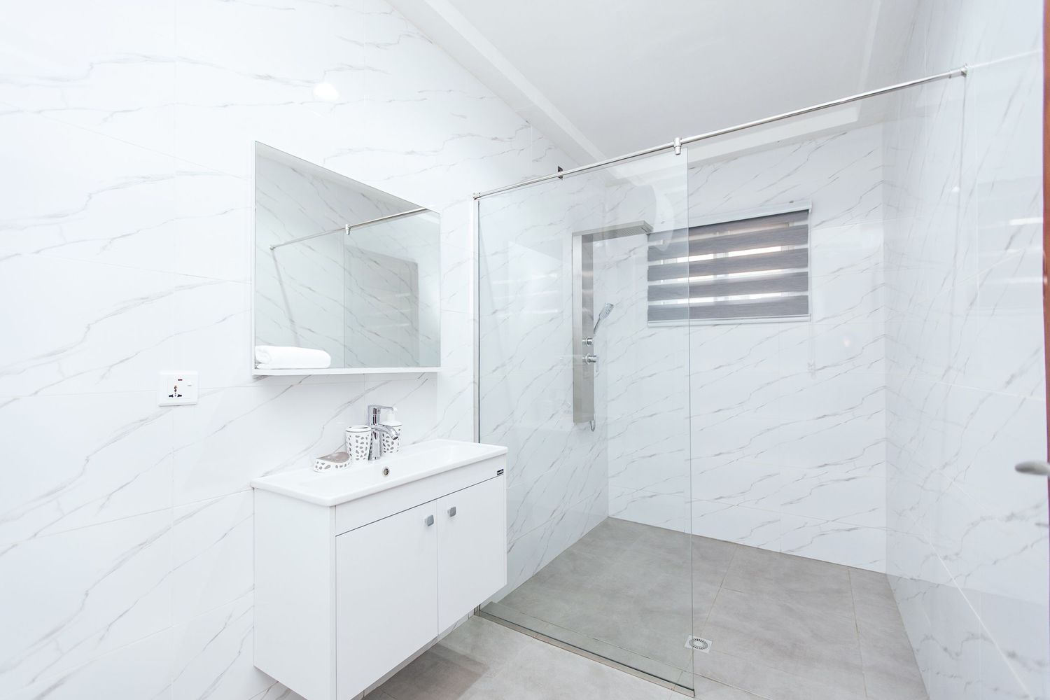 Luxurious white marble bathroom with glass shower enclosure and modern fixtures.