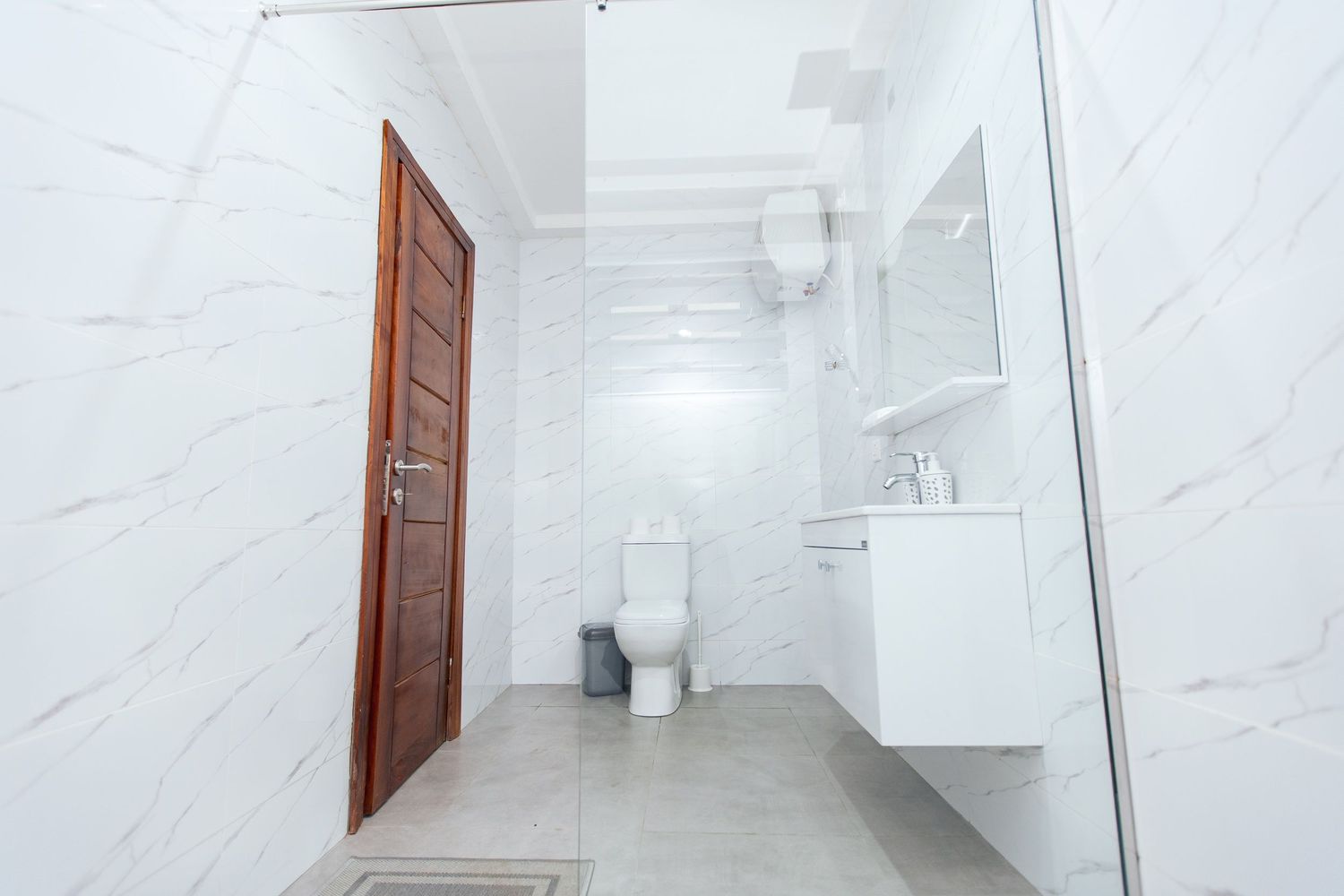 Contemporary bathroom featuring white marble tiles and glass shower partition.