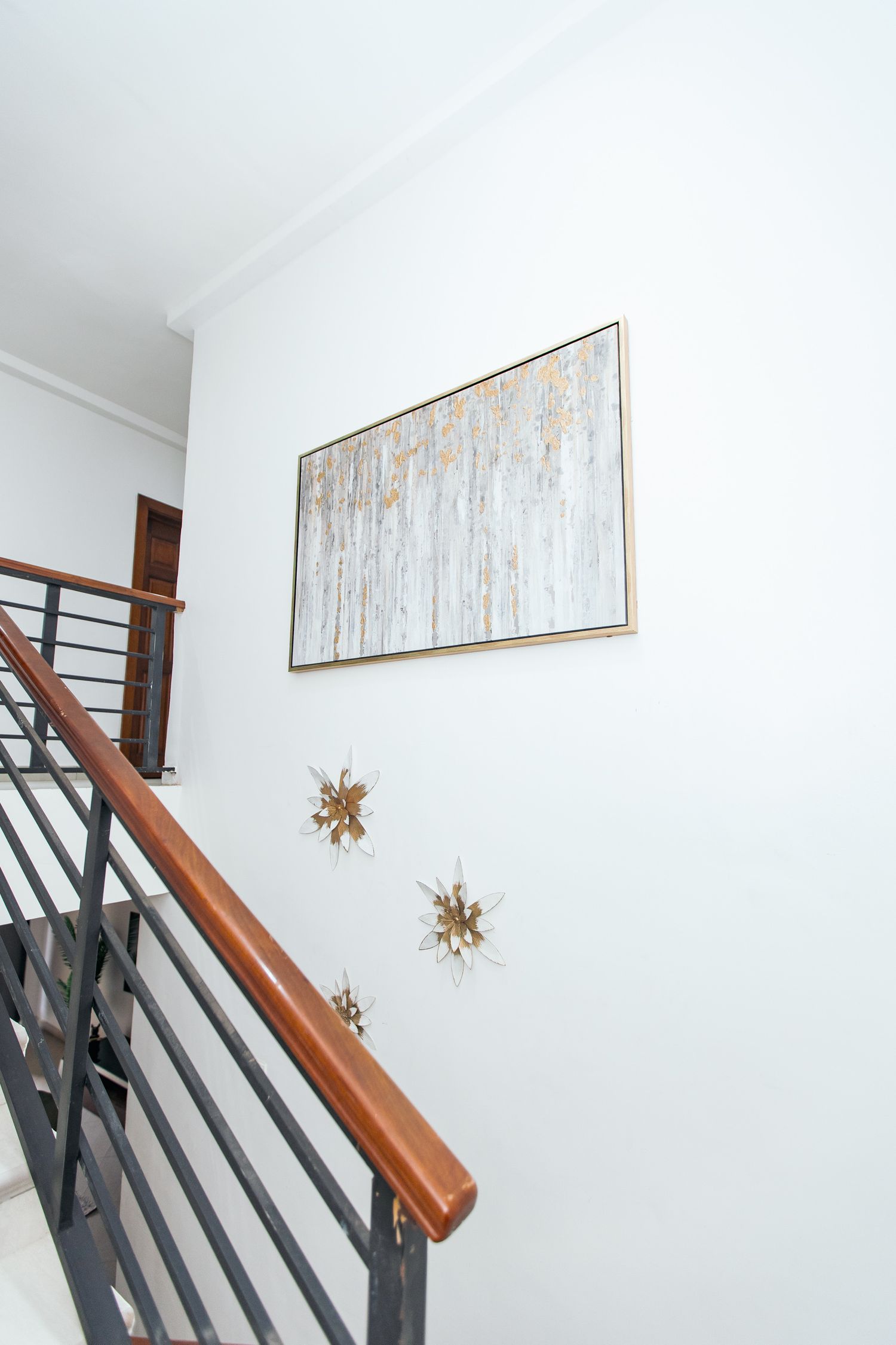 Modern staircase with black metal railings, wooden handrail and abstract wall art.