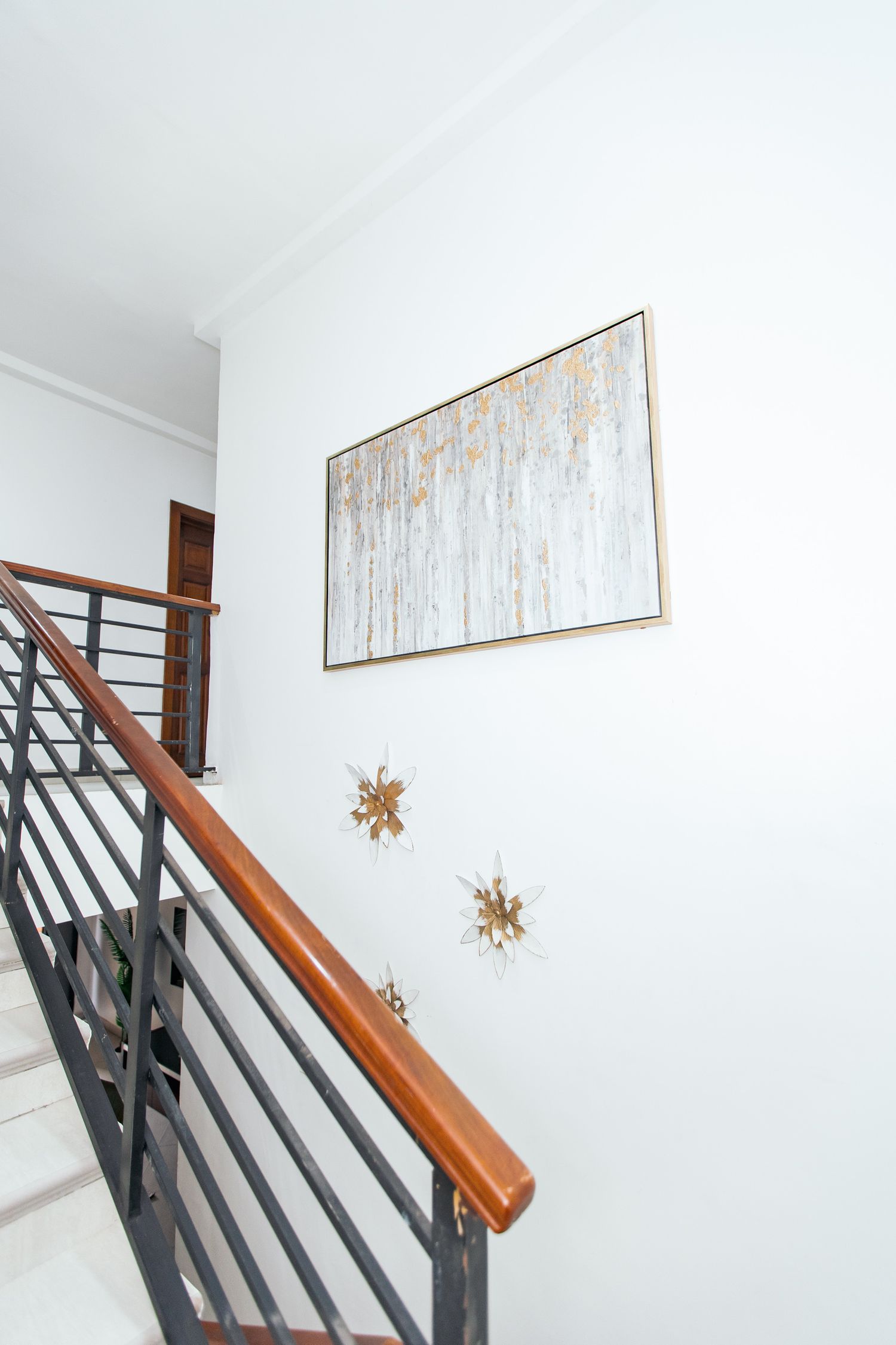 Elegant stairwell with wooden and metal banister featuring decorative wall accents.