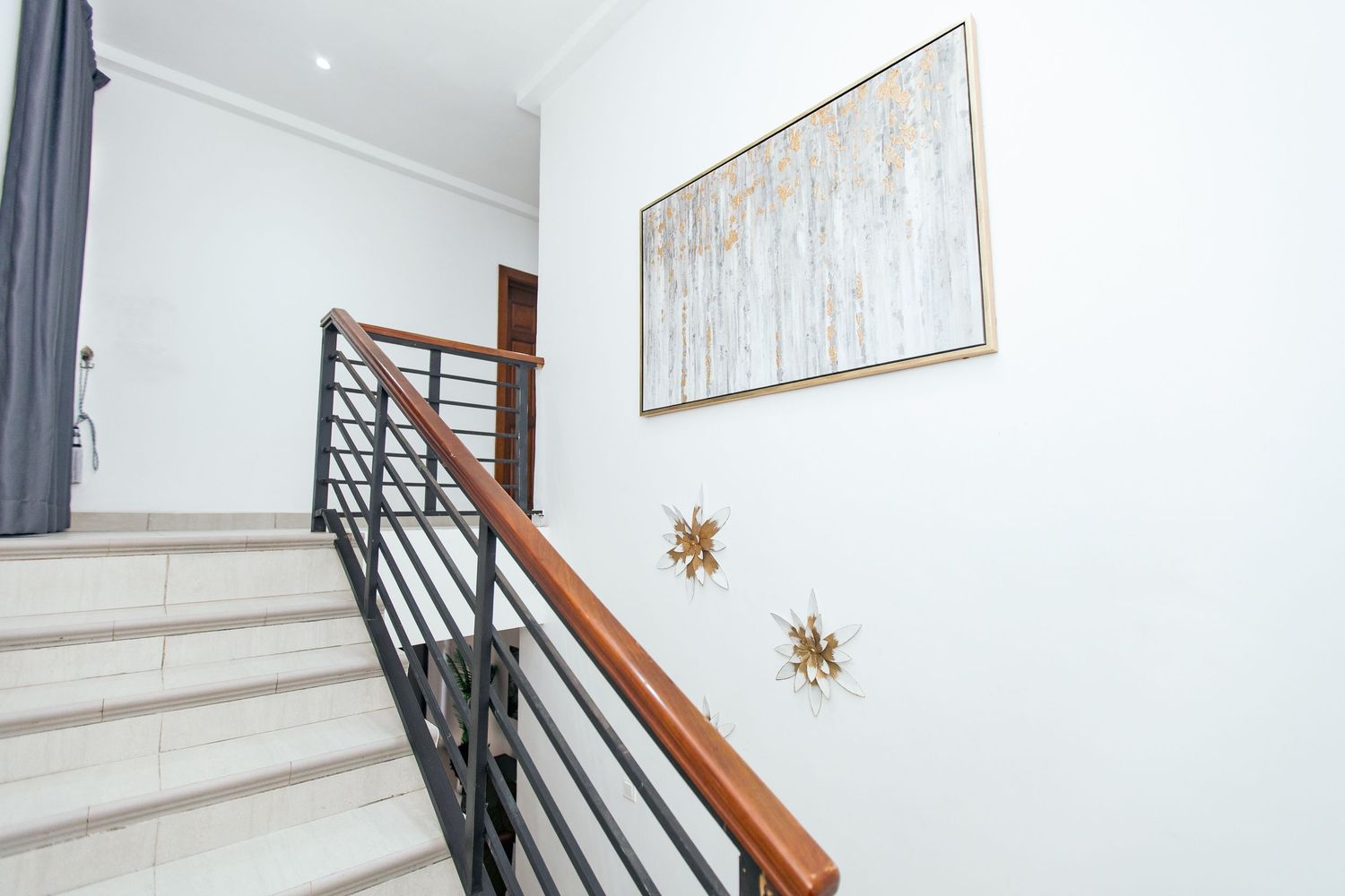 Modern white interior staircase with black metal railing and wooden handrail in a minimalist home design.