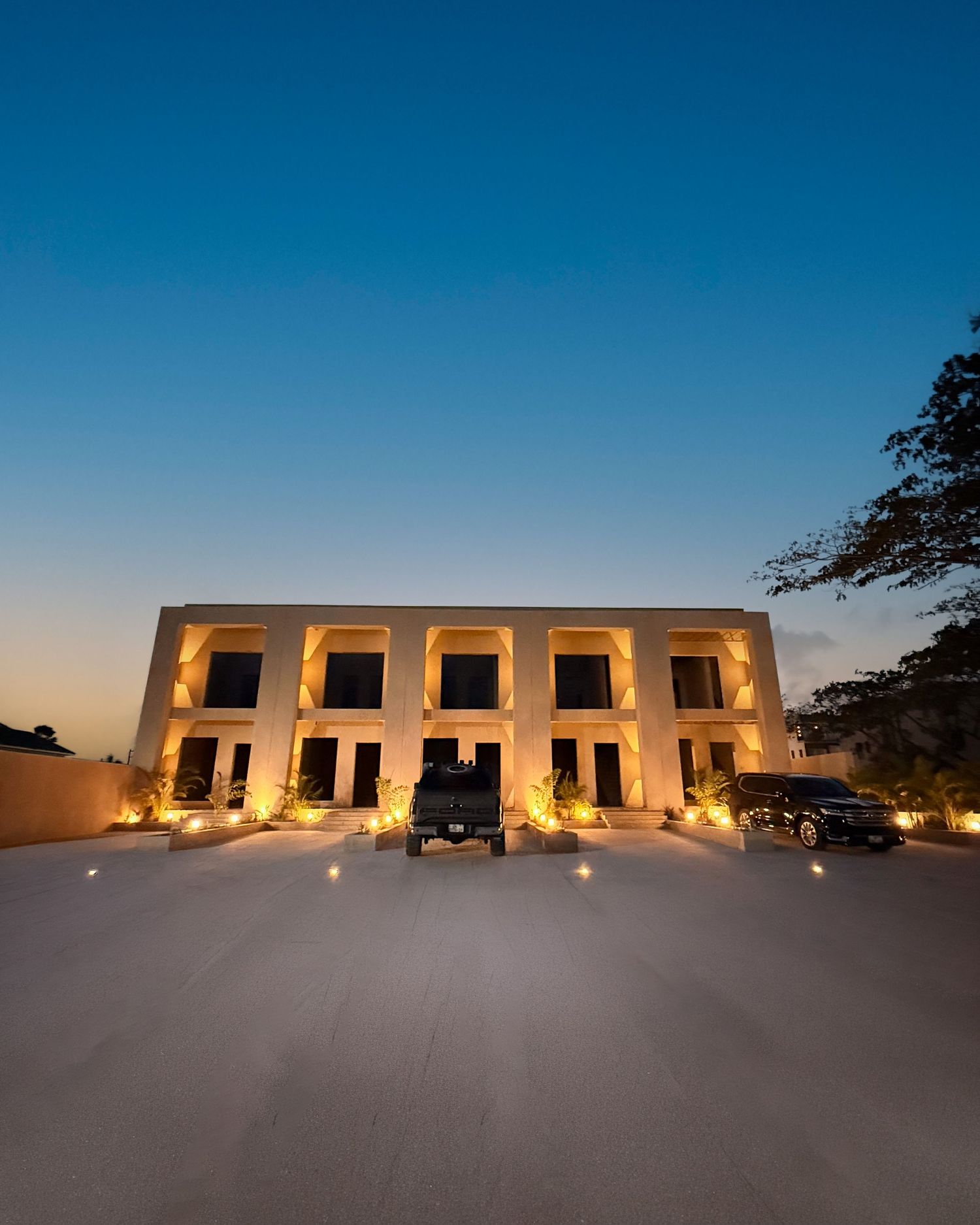 Desert resort building illuminated at sunset with multiple square windows and glowing lights against a deep blue sky.