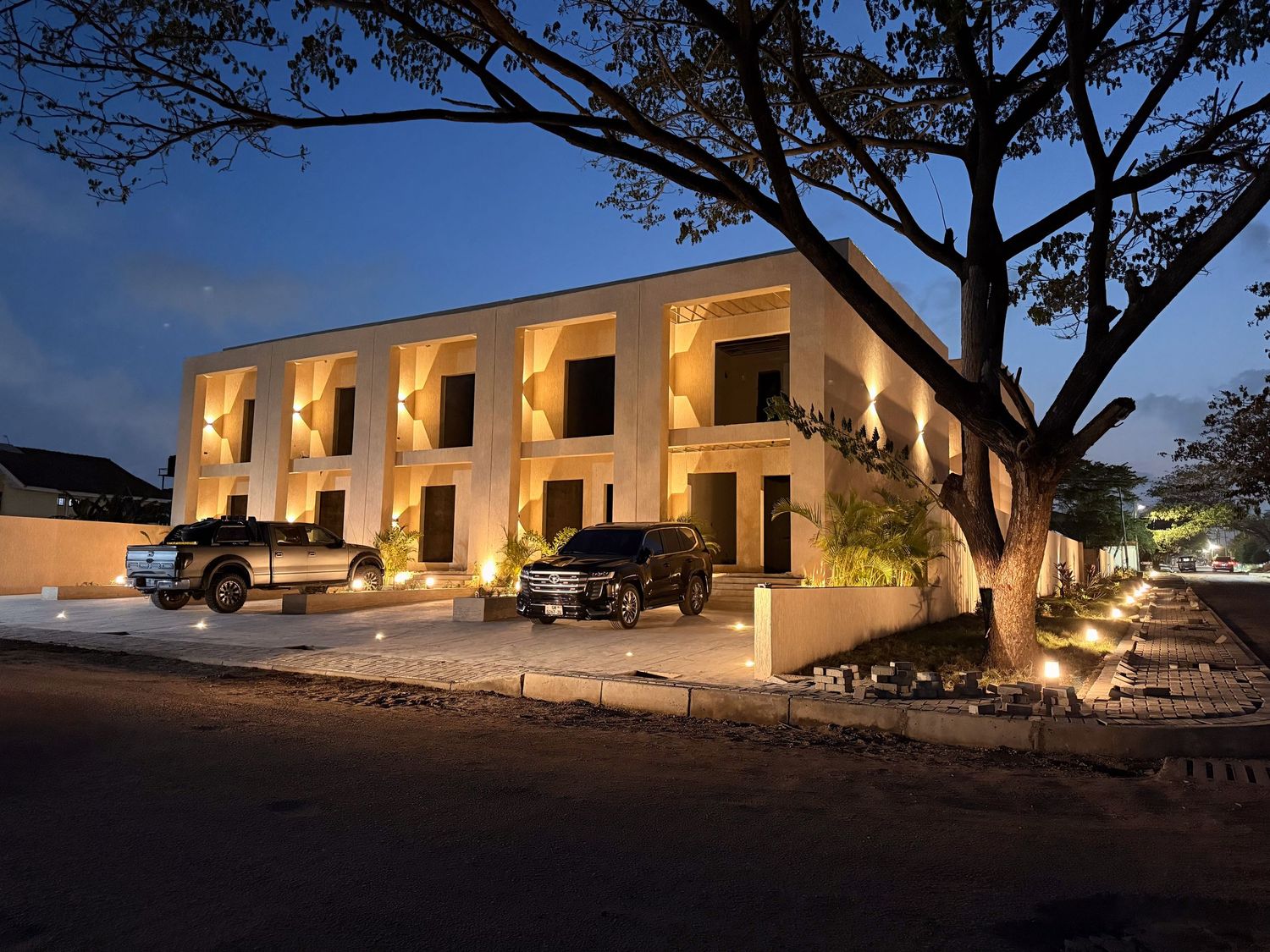 A luxurious white villa illuminated at dusk with outdoor lighting creating a warm glow along its Mediterranean facade.
