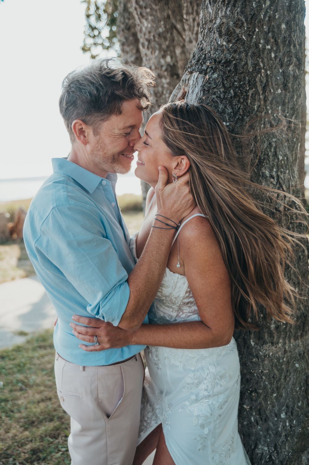 A couple shares intimate romantic moments together against a tree trunk in a series of outdoor wedding photos.