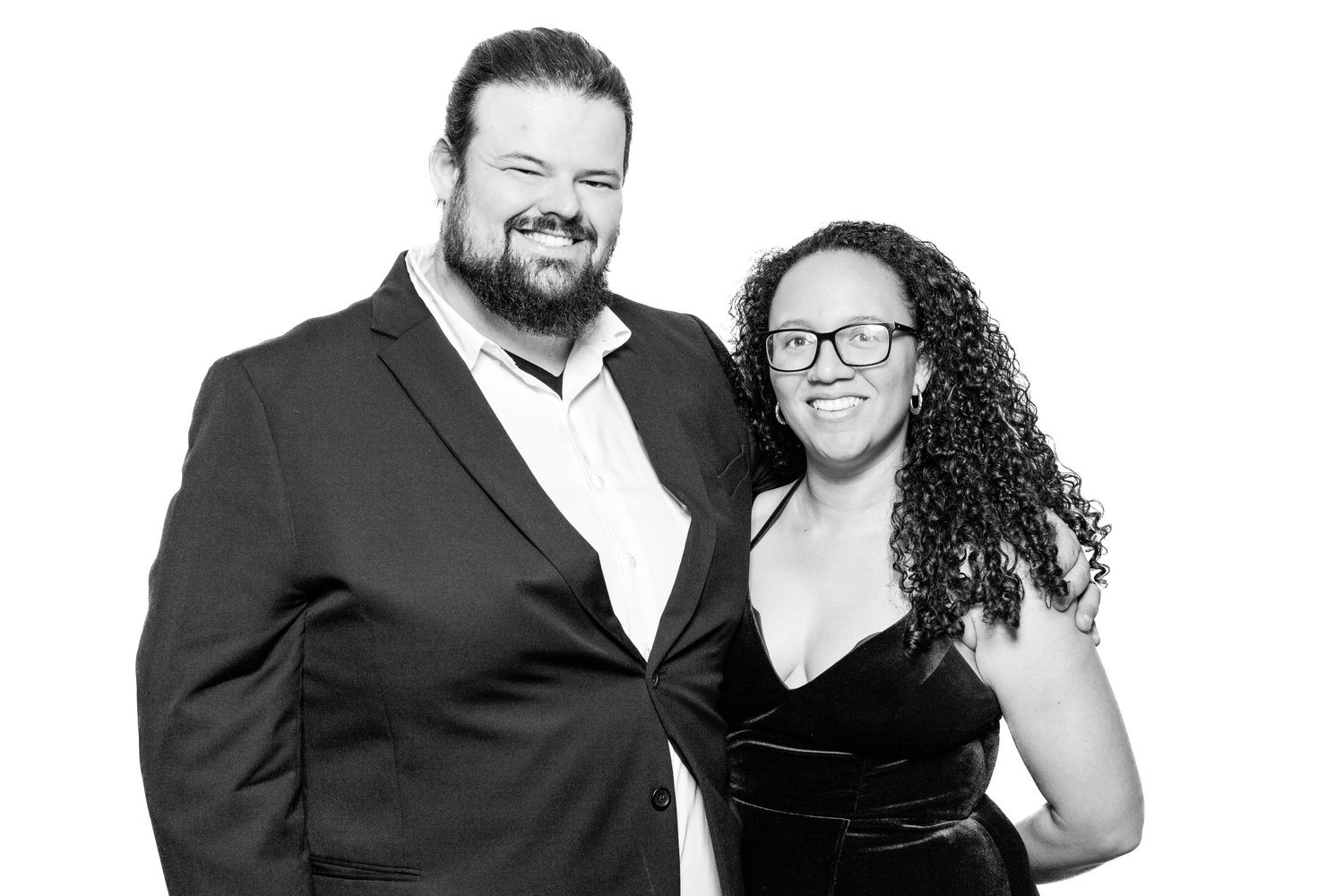 Elegant black and white portrait of a couple in formal attire sharing a joyful moment together.