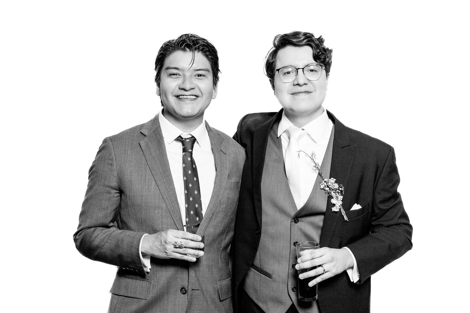 Candid black and white shot of two people in formal wear sharing drinks and conversation.