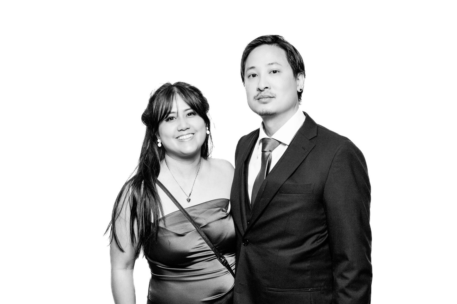 Black and white portrait of a couple in evening attire smiling at the camera.