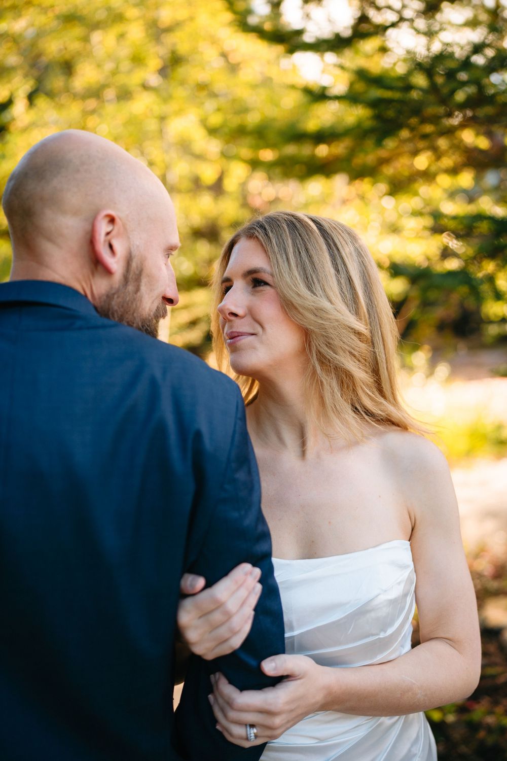 A romantic moment between newlyweds captured in golden sunlight with trees in the background.