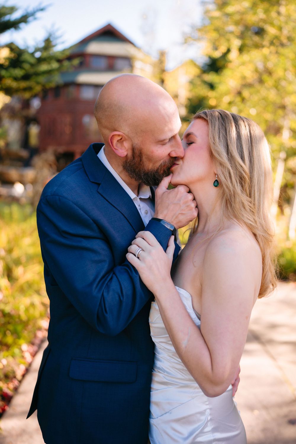 A romantic wedding couple shares intimate kisses against a golden autumn backdrop.
