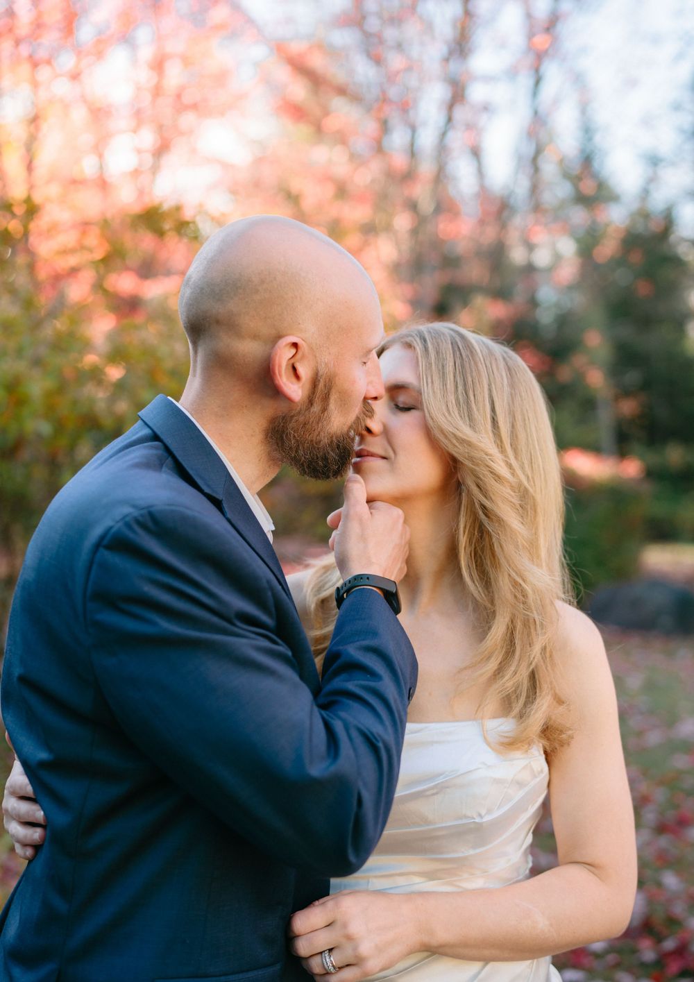 A romantic couple shares tender kisses in a series of photos with autumn foliage in the background.