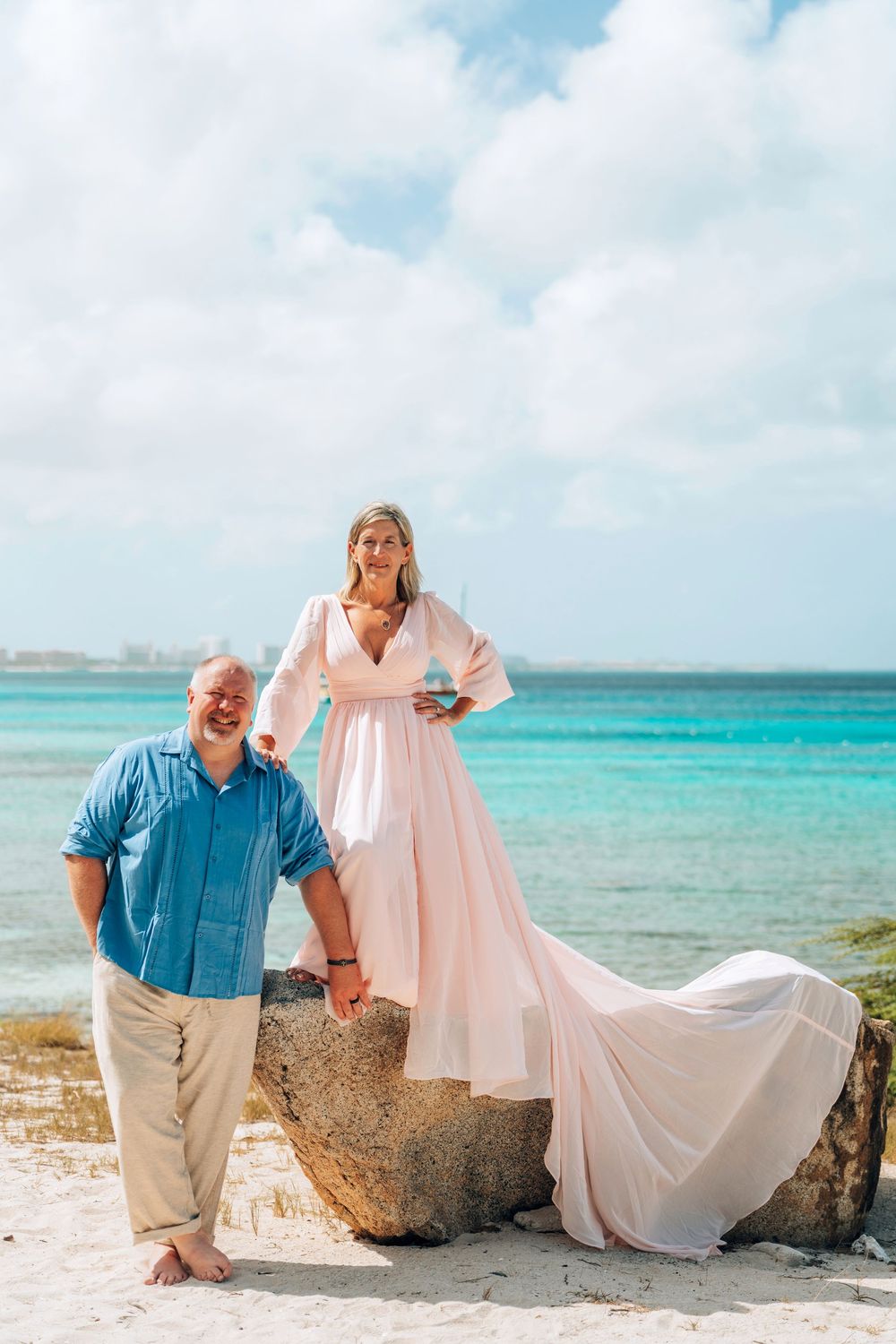 Romantic beach photoshoot sequence showing couple posing playfully with flowing dress against turquoise ocean backdrop.