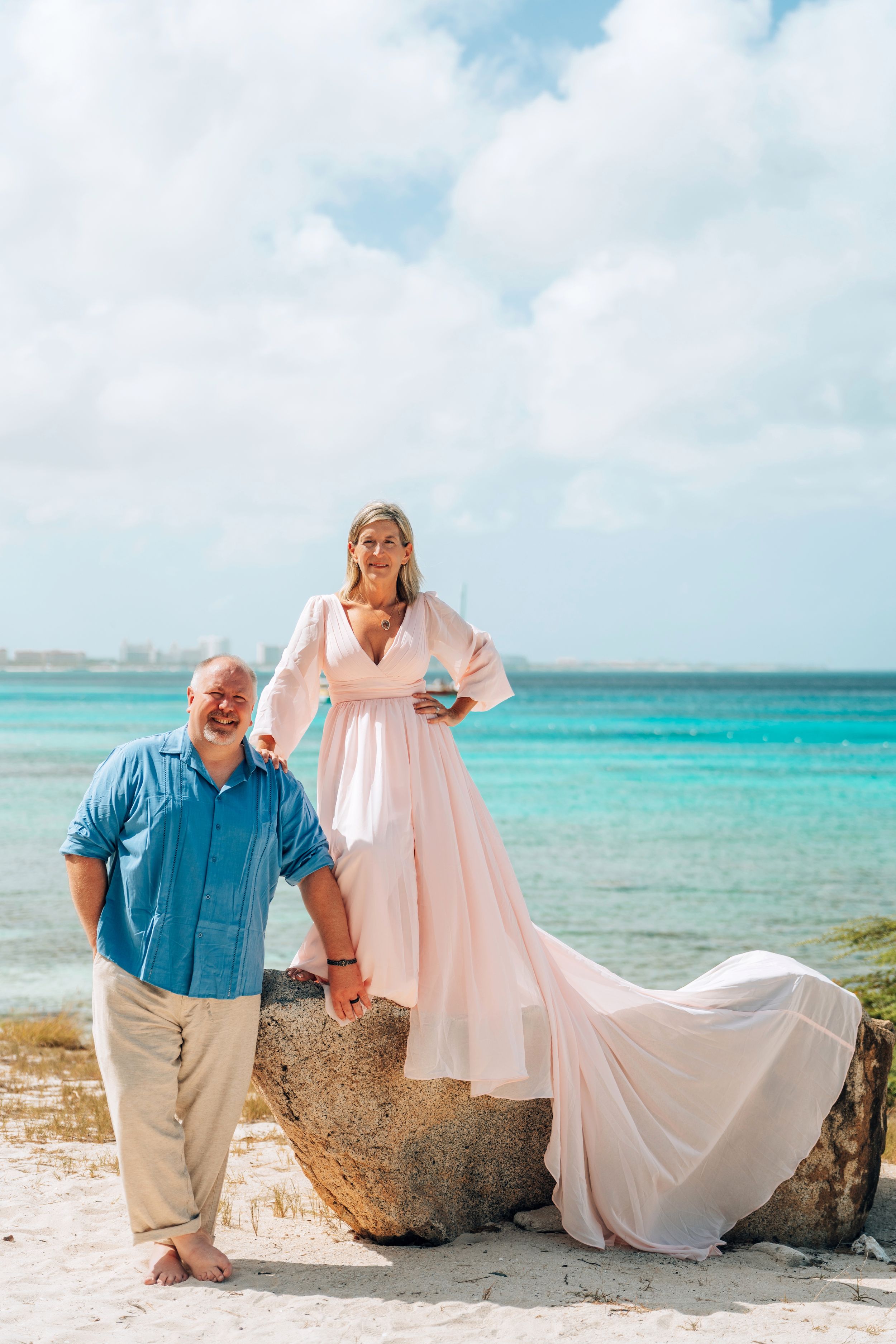 Romantic beach photoshoot sequence showing couple posing playfully with flowing dress against turquoise ocean backdrop.