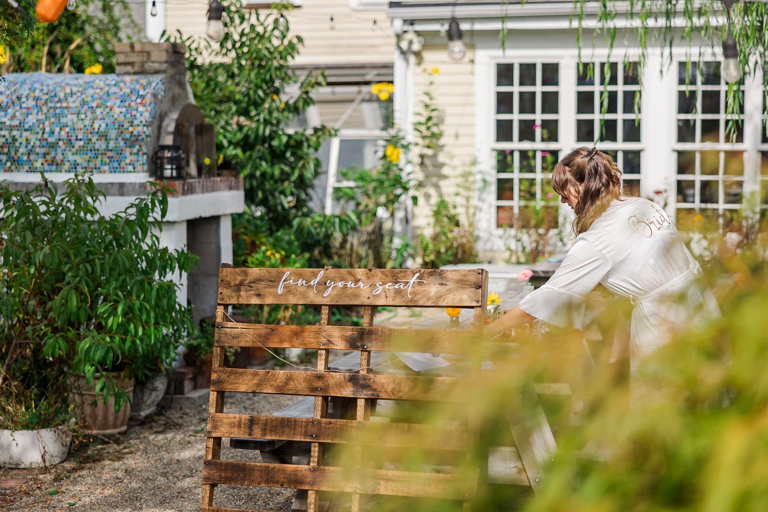 Rustic wooden benches arranged in rows create an intimate outdoor seating area in a garden setting.
