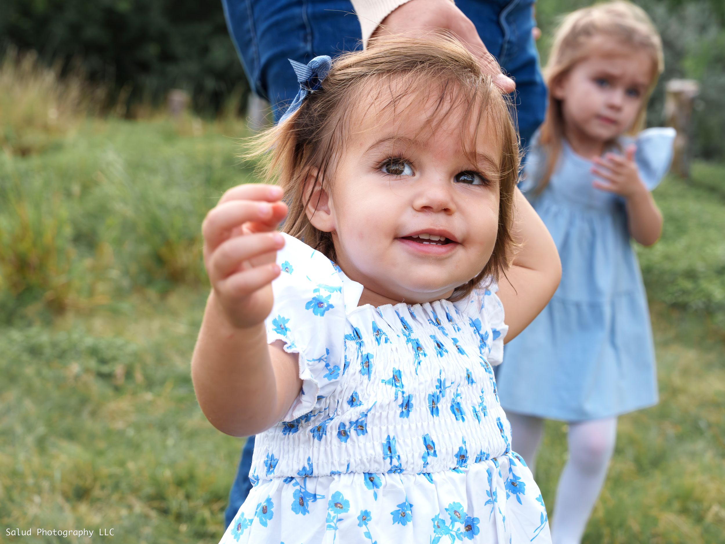Little girl in a blue and white patterned dress playing outdoors in summer.