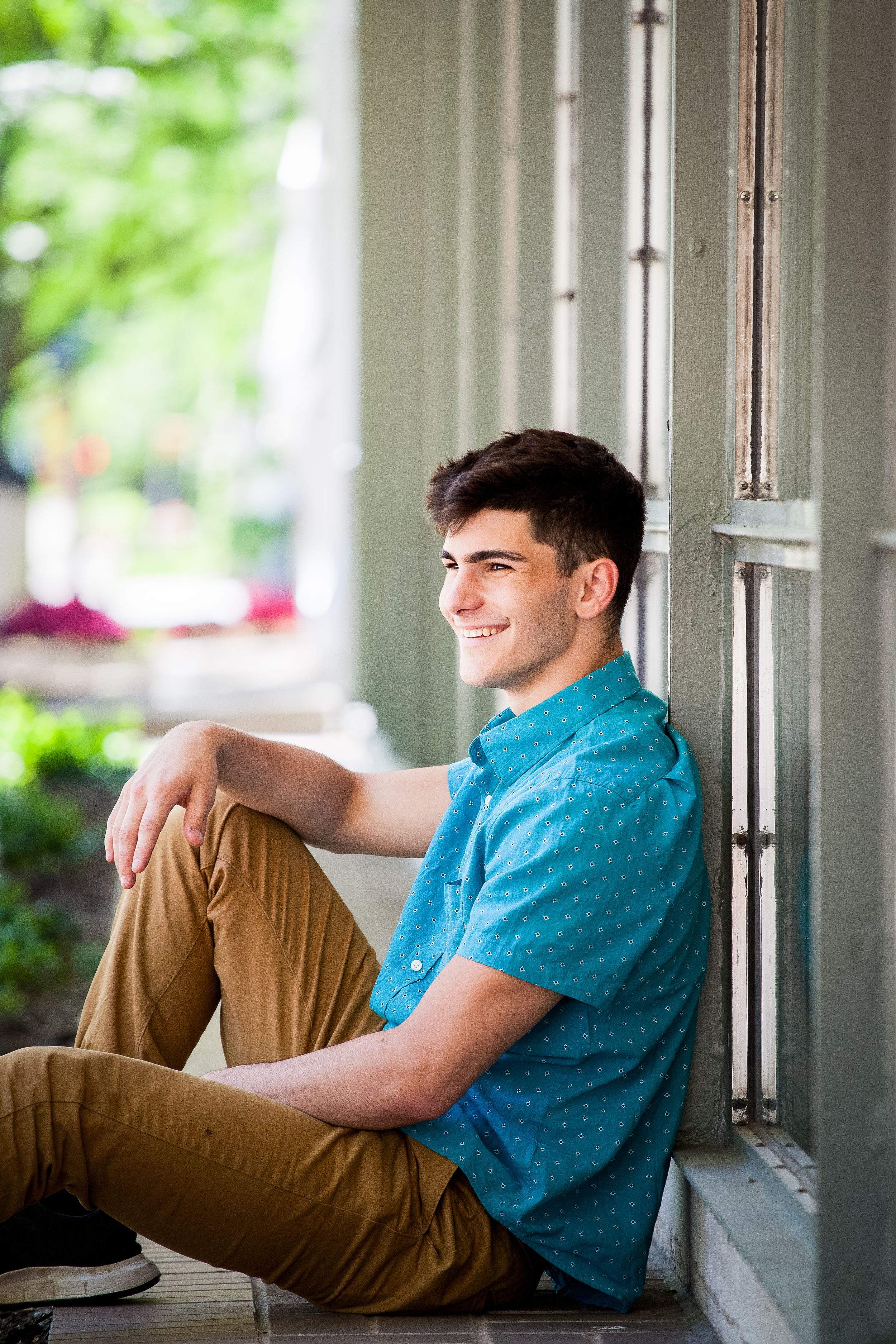 A young person in a blue shirt and khaki pants sits casually by a window in a series of connected photos.