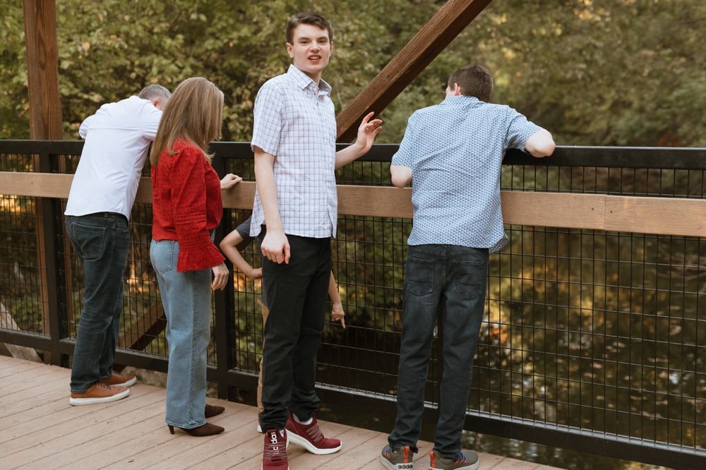 A group of people lean over a wooden railing on a bridge deck to look at the scenery below.