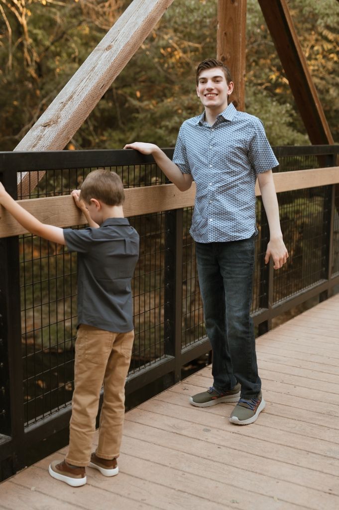 Candid shots of family members walking and posing on a wooden bridge surrounded by autumn foliage.