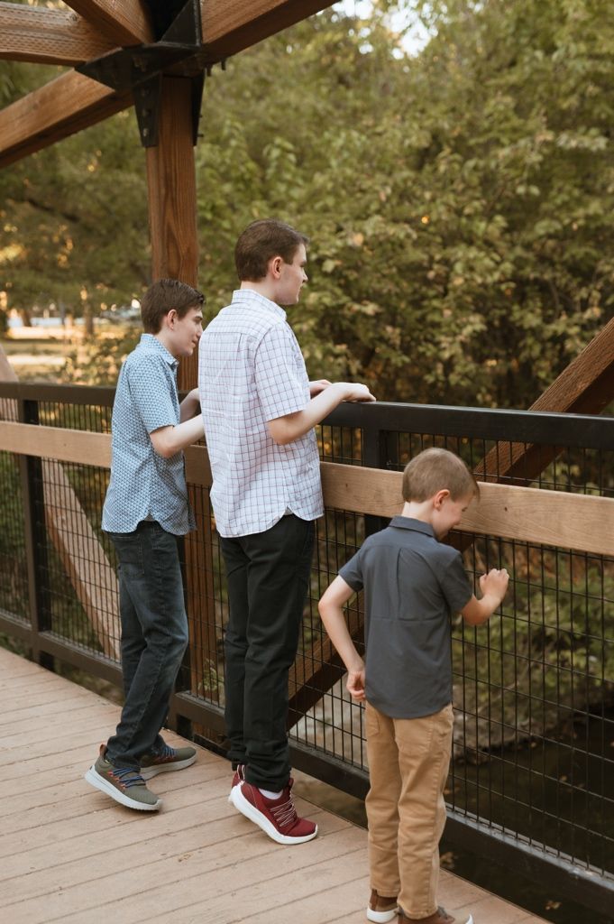 People standing on a wooden observation deck peering over the railing into the distance.