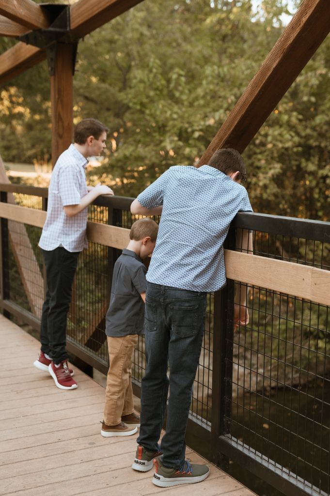 Multiple views of people looking over a wooden deck railing surrounded by trees.