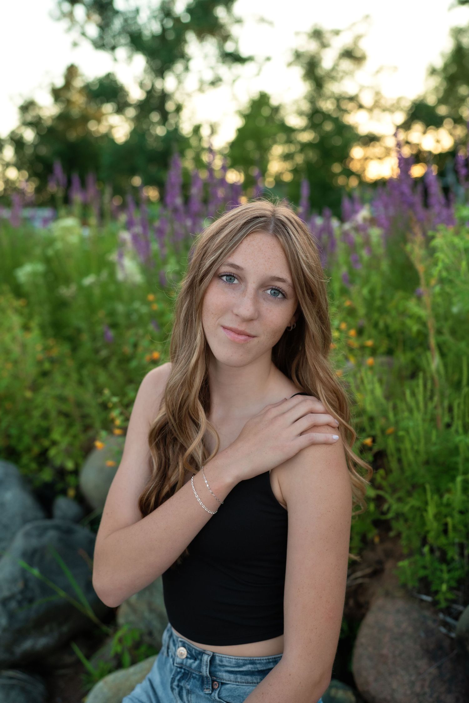 Sunset portrait session among purple wildflowers and natural garden landscaping.