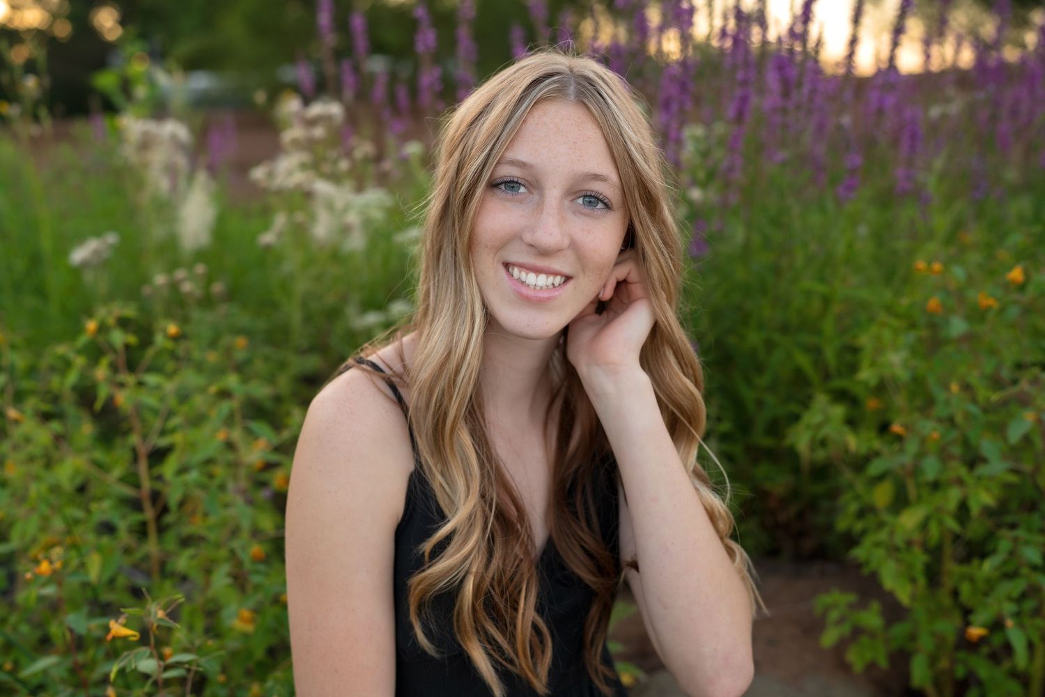 Summer portrait session in a field of vibrant purple wildflowers during golden hour.
