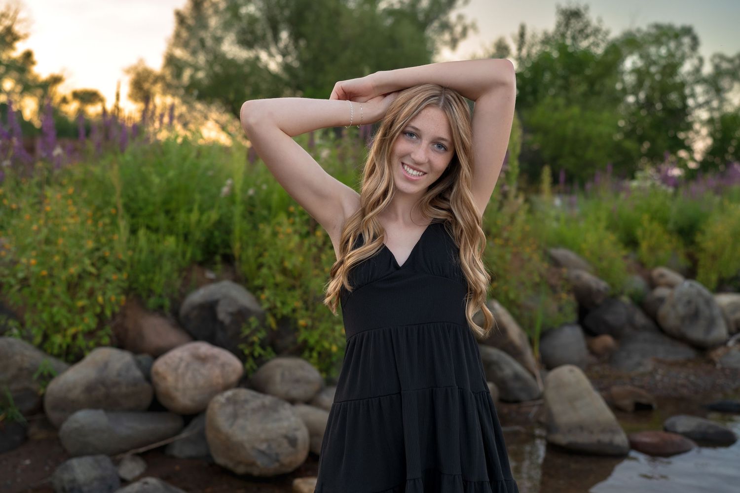 Natural light portrait against a rustic stone wall with golden evening sunlight.