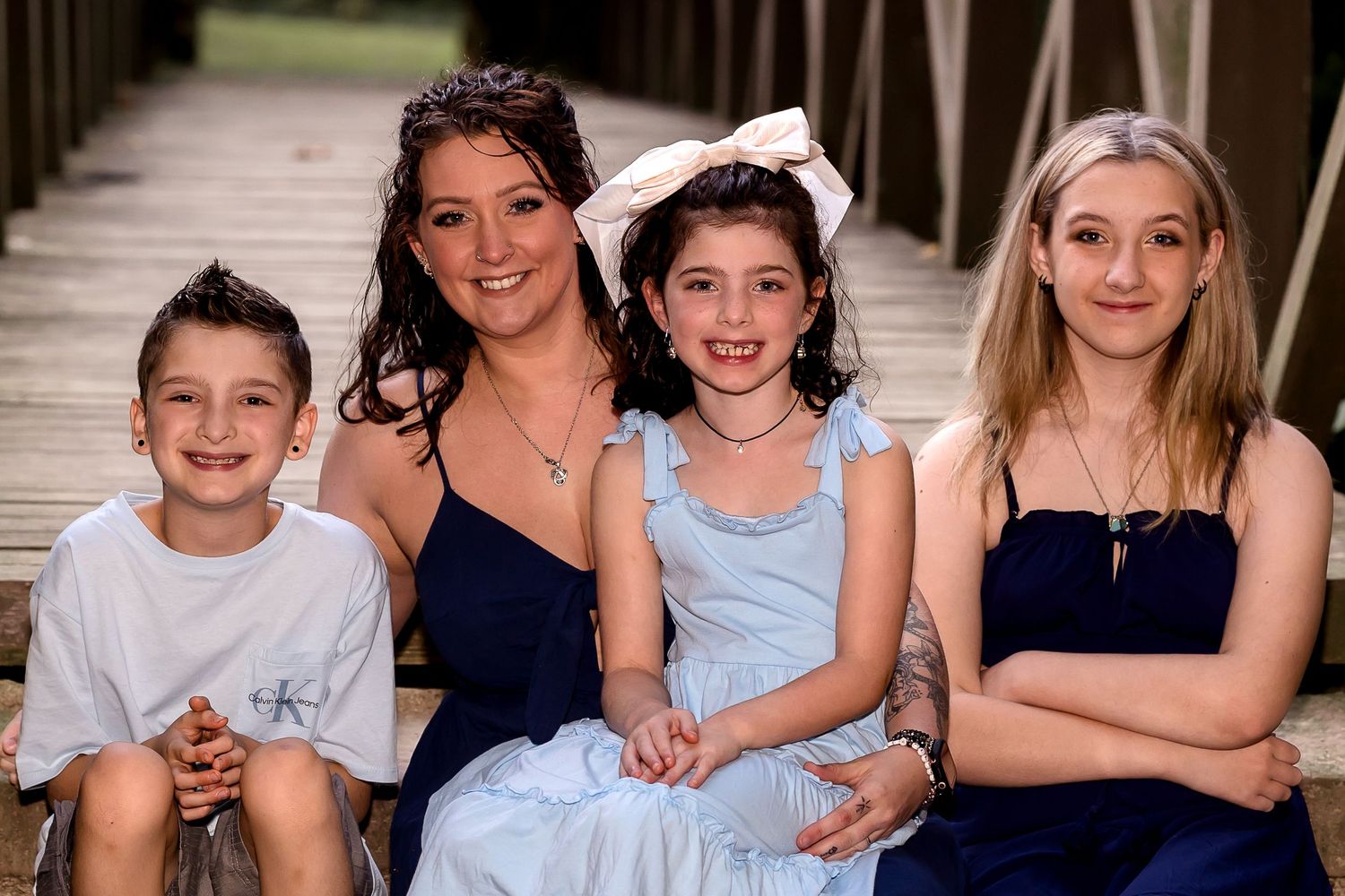 Group portrait of children sitting together on wooden deck in coordinated outfits.